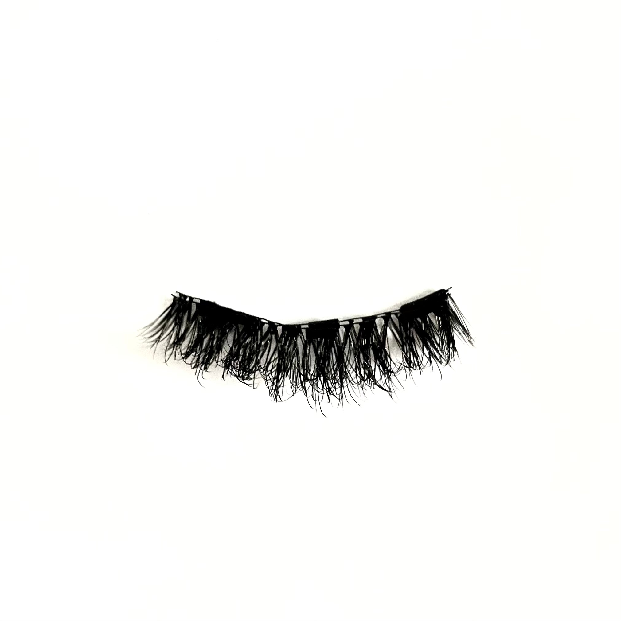 Close-up of fluffy, curled, doll-eye false eyelashes in the ‘Stargirl’ style on white background.
