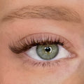 Close-up of a green eye wearing natural, small brown cat-eye false eyelashes on the upper lash line