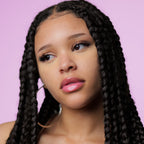 Woman with long braided hair against a pink background